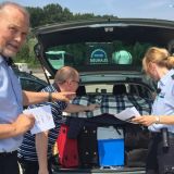 Zwei Polizisten beraten einen Mann am Autobahnrastplatz zur Ladungssicherung am Kofferraum eines Autos