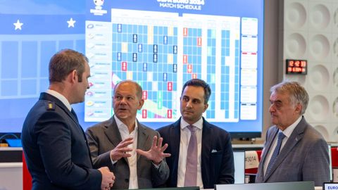 Der Leiter des IPCC 2024, Oliver Strudthoff, erklärt Bundeskanzler Olaf Scholz, Staatssekretär Mahmut Özdemir und Innenminister Herbert Reul, wie die Zusammenarbeit von Polizistinnen und Polizisten aus verschiedenen Nationen, organisiert ist.